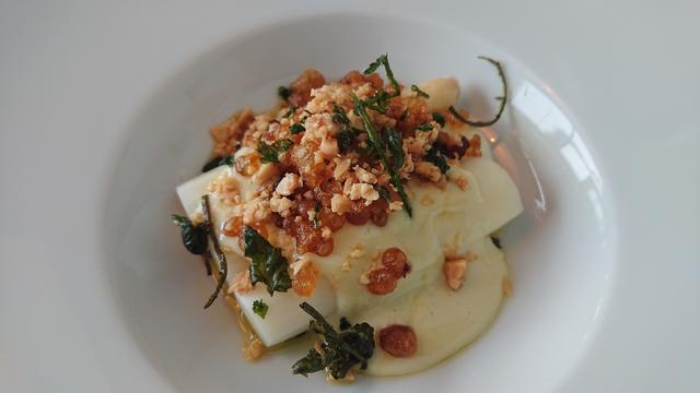 A starter with white asparagus, sauce, nuts and greens