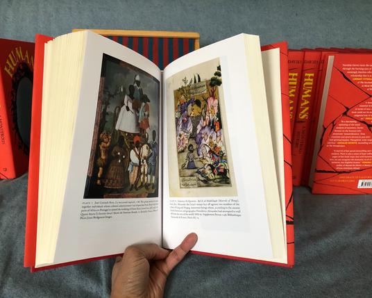 Hardback book open to colour plates, with one large plate on each page. The plates show richly coloured scenes of people. Left: Seven African-descended people and one Indigenous American (dressed in feather garments and with a bow and arrow) are arranged in three tiers. All but one figure is in fine European clothing; most are short and stocky, or proportioned like children. Right: Turbaned soldiers, some on horseback, watch a naked woman scaling a wall between two cliffs; a male figure, naked from the waist up, rises out of a river.
