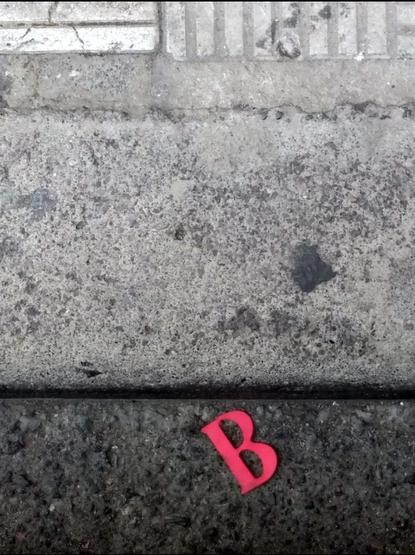 Letra Be roja en el suelo d la calle.