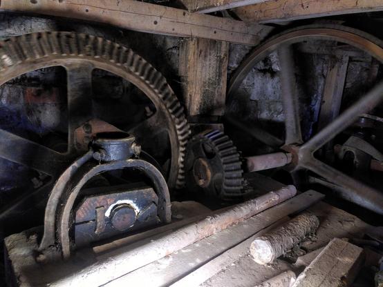 Große Zahnräder innerhalb der Mühle, sie lenken die Energie des Wasserrades zu den Gerätschaften in der Mühle. Die Zahnräder sind unscharf, da sie in Bewegung sind.