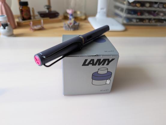 bottle of Lamy Pink Cliff Ink on a desktop. On top of the bottle there is a Lamy Safari Pink Cliff fountain pen.