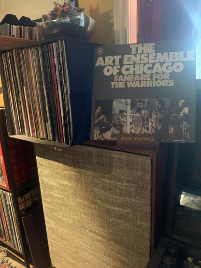 Fanfare For The Warriors cover sits atop a vintage custom speaker with record stacks in the background