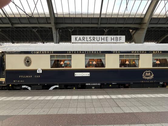 Ein altmodischer Pullmann-Zugwagen mit der Aufschrift „Compagnie International des Wagons - Lits et des Grands Express Europees“ in goldfarbigen Lettern.
Die Wagen haben 7 Fenster, mit jeweils links und rechts Vorhängen darin. Auf den Tischen stehen kleine leuchtende Lampen. Die Wagen sind verziert mit am Anfang und am Ende einem kleinen mehrteiligen Schmuckfenster. Das auf dem Bild ist ein Speisewagen.