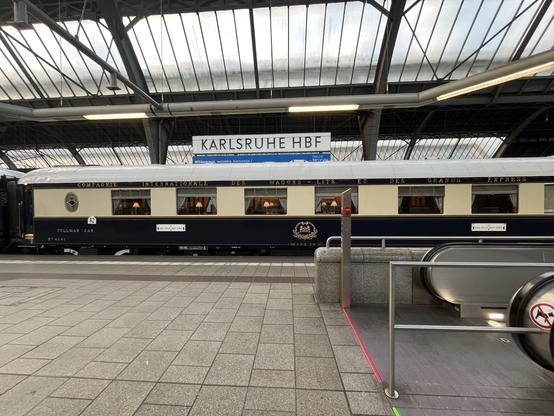 Ein Foto von einem Speisewagen des Orientexpress von weiter weg aufgenommen, allerdings mit der Rolltreppe im Vordergrund.