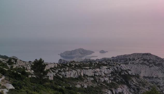À l'heure pour le coucher de soleil, mais le voile dense dans le ciel ne permet pas de le voir. Seule la lumière diffuse dans l'air montre une dominante rouge orangé dans le ciel.

La photo est prise au sommet de Marseilleveyre en direction de l'ouest.

On y voit Béouveyre l'antecime du massif, puis en arrière plan l'ile Maire dans une mer qui se fond avec le ciel, l'horizon est peu distinct due à ces couleurs peu saturés.
