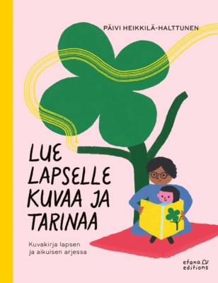 Lue lapselle kuvaa ja tarinaa -kirjan kannessa on piirros aikuisesta lukemassa lapselle kirjaa ison nelilehtisen apilan juurella.