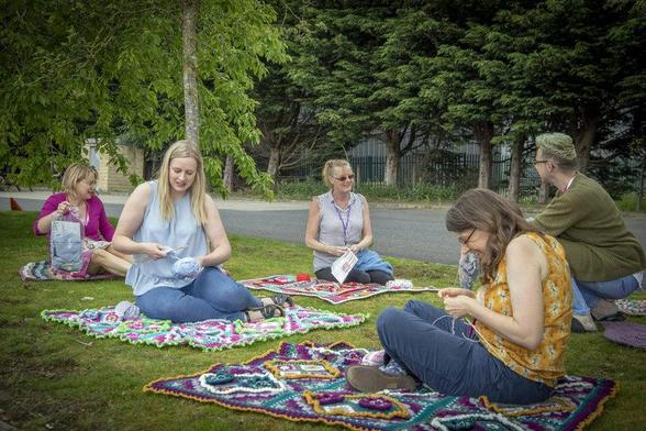 Installées dans un parc public, des personnes tricotent