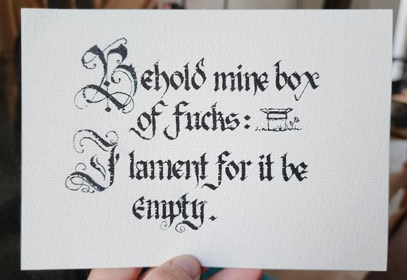 Calligraphed in black ink  Blackletter script with fancy swirly majuscules, and a little drawing of an empty box on grass:

Behold mine box of fucks:
I lament for it be empty.