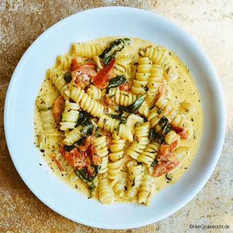 Steinplatte. Darauf ein runder Pastateller. Darin: Fusilli mit Tomaten, Spinat, Knoblauch und Thymian