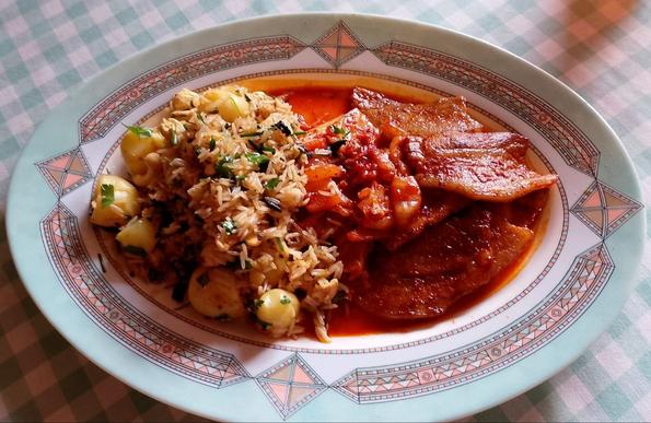 Un plato plano ovalado grande. En él de izquierda a derecha: arroz frito con cosas, kimchi y panceta adobada.
Excepto el arroz que tiene un color amarillento el resto del plato podría describirse como rojo rabioso.