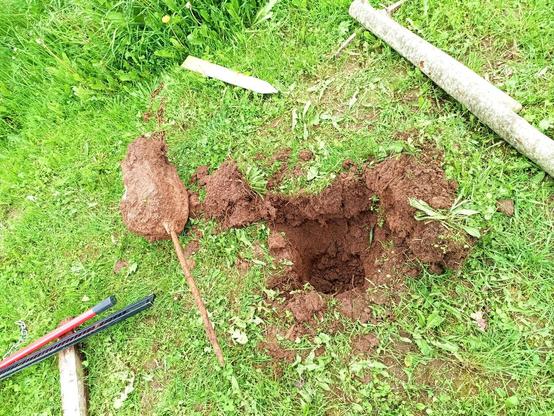 The extracted mooring post with concrete block cast around it, a bunch of ripped out topsoil and a  deep hole in the ground.
