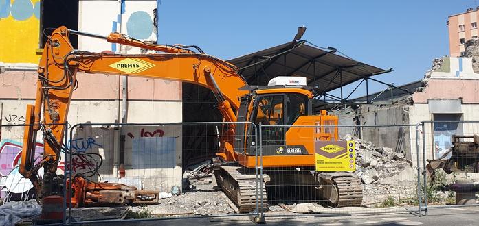 Photo d'une pelleteuse et d'un bâtiment en cours de destruction.