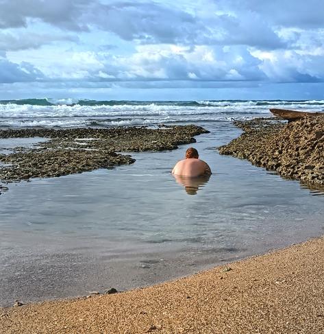 Color photo of non surfing side of Cocles Beach in Costa Rica. Redhair young man looks at colorful caribbean fish in the small pools among coral walls. Still warm and sunny in June !