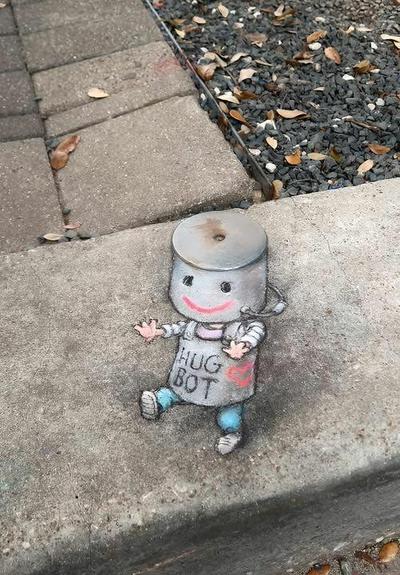 The image shows a piece of sidewalk chalk art by David Zinn, depicting a character he calls "Hug Bot".