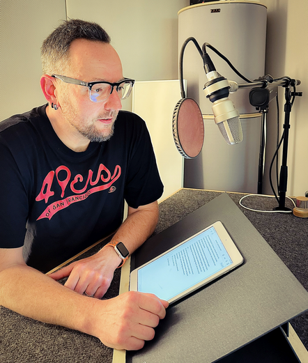 Daniel Holbe im Tonstudio mit Mikrofon und Skript.