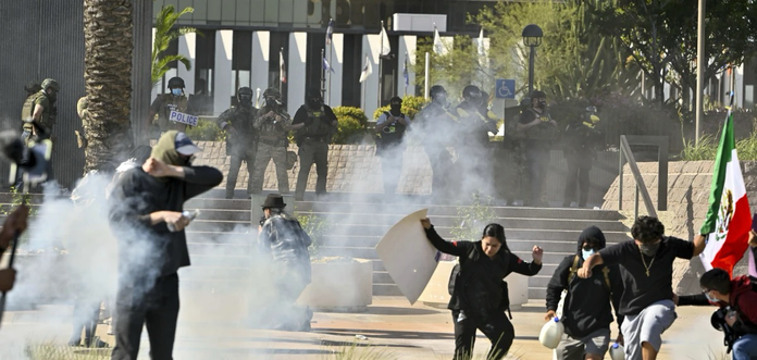Protesters run from police as they use tear gas and flash-bangs at the Federal Building in Santa Ana, Calif., on Monday, June 9, 2025. (Jeff Gritchen/The Orange County Register via AP)