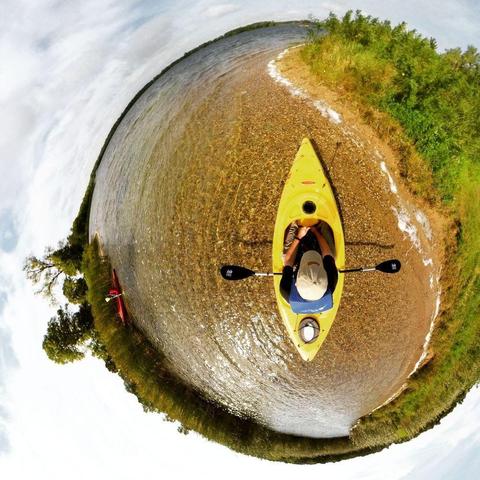 One of a series of photographs in which two people are pictured hiking, biking, and kayaking throughout a beautiful and verdant state park in central Minnesota under cloudy blue late-summer skies.