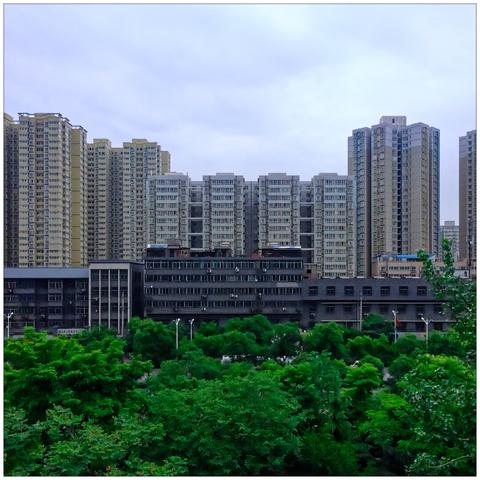 View from the elevated city wall at residential highrises with greenery in the foreground.