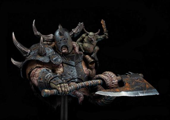 The photo captures a remarkable, intricately painted miniature sculpture that exudes a sense of menace, grotesque beauty, and chaotic energy. The central figure is a hulking, grotesque warrior with distorted, fleshy features and grotesque musculature. His armor, battered and corroded, is adorned with jagged horns that curve outward, adding to his intimidating silhouette. The armor’s dark, rusted tones contrast with the fleshy pink and diseased-looking textures of his exposed skin, suggesting a creature corrupted by some dark force. His helmet, partially concealing his bloated face, has slits for the eyes, and his gaping mouth reveals jagged teeth, amplifying his monstrous presence. The attention to detail in the craftsmanship is extraordinary, creating a scene that feels alive and bursting with personality.