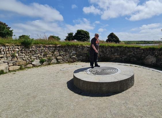 A dowser standing over a circular dais with an infused labyrinth design.