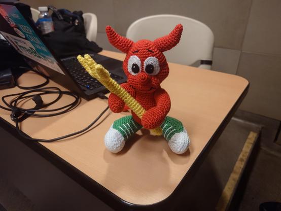 Red Crotchetty BSD Daemon Beastie with Yellow trident and green-and-white shoes. very cute!