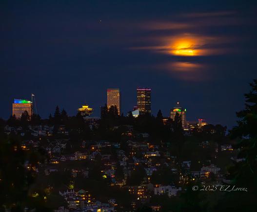 Full moon rises behind the cloud cover, illuminating them over the skyline of Seattle last night.
