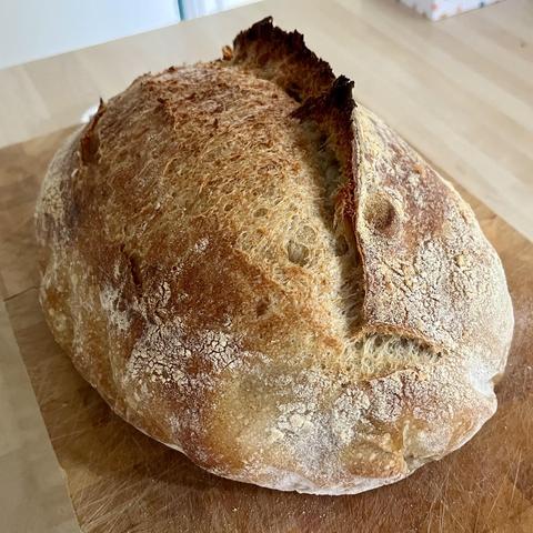 Sourdough loaf on wooden chopping board. The bread has a distinct ‘ear’.