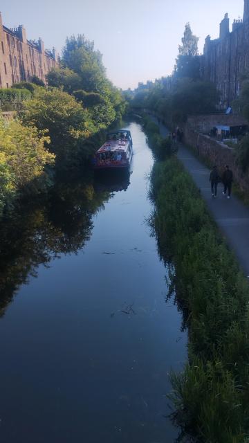 Barge sailing along the Union Canal between rows of Victorian stone tenements, children sitting at the bow of the boat