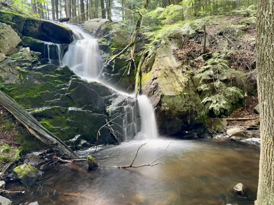 Long exposure of a waterfall near Smith pong on New Hampshire. Water cascading down into a pool via moss covered rocks