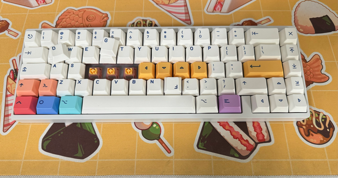 Virtually the same keyboard as above, bright colored modifiers and pale plain alphas, just against a food-themed deskmat. Some of the keycaps are off and strewn about to reveal the switches, Outemu Honey Peach v3.