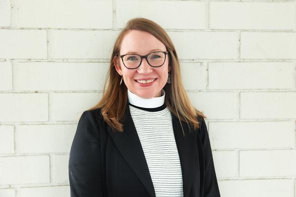 A woman in glasses and a clerical collar smiling.