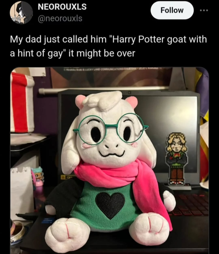The image features a tweet from the user "NEOROUXLS" with the handle "[@]neorouxls." The tweet reads: "My dad just called him 'Harry Potter goat with a hint of gay' it might be over." Below the text is a photo of a plush toy resembling a goat with white fur, pink ears, and glasses. (character from deltarune) The toy is wearing a green outfit with a black heart on the front and a pink scarf. It is sitting on a laptop keyboard. In the background, there is a laptop screen displaying a pixel art image of a character, and various items are visible on the desk, including a red and white striped object and a small figurine.

Provided by @altbot, generated privately and locally using Ovis2-8B