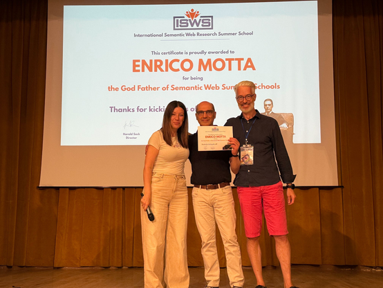 On stage: Valentina Presutti, Enrico Motta, and Harald Sack, in front of Enrico Motta's honorary certificate for being the ISWS Godfather.
