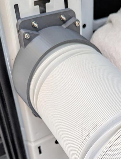 A photo of the rear column of a cargo van with an air outlet mounted on it and a 5" tube connected to that.