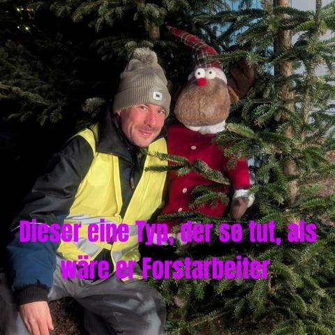 Ich in Warnweste neben einem Plüschtier Rentier und im Hintergrund eine Fichte