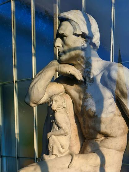 A statue of a naked man with a monkey sitting on his lap.