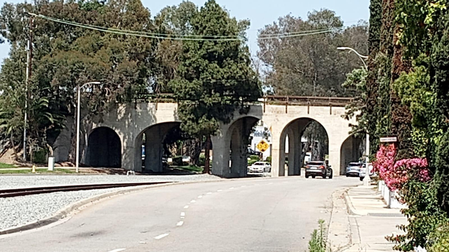 an arched cement bridge, tracks go under one arch, roadways and sidewalks under the rest