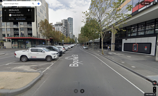Wide ugly road in Docklands Melbourne showing how desolate the place looks. This photo has a load of cars parked in the middle of the street.
