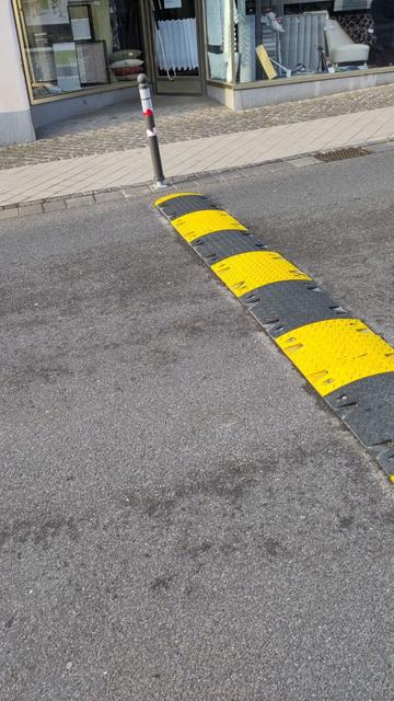 Schwarz gelbe Bodenschwellen auf der Fahrbahn und Poller auf dem Bürgersteig