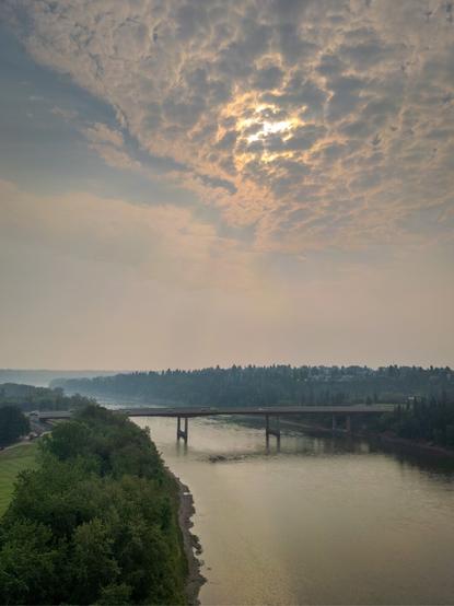 The morning sun is blocked by clouds and wildfire smoke, creating an eerie landscape above Edmonton.