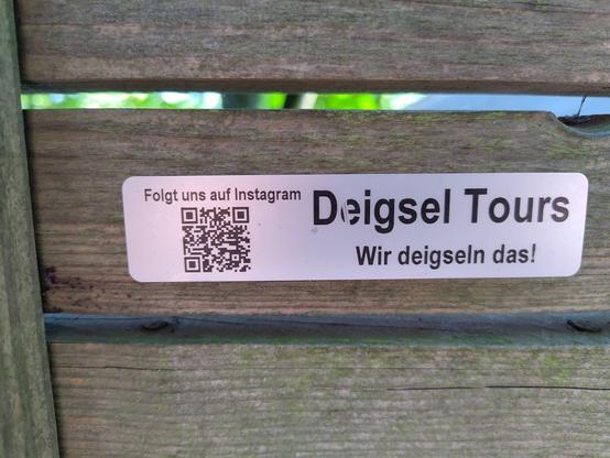 Aufkleber an Holzzaun mit Aufschrift "Deigsel Tours Wir deigseln das!"