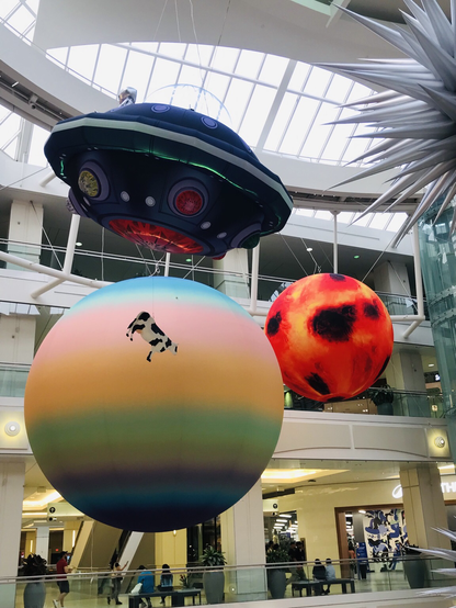 Metrotown mall display: cow being abducted by a spaceship; Trans planet & maybe the sun?