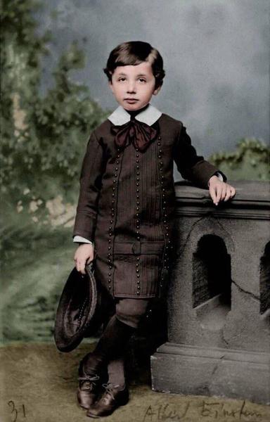 Ein historisch koloriertes Porträt des jungen Albert Einstein, etwa im Alter von 5–6 Jahren. Er steht in feiner Kleidung – ein dunkler Anzug mit dekorativen Knöpfen, weißem Kragen und großer Schleife – vor einer klassizistischen Steinkulisse. In seiner linken Hand hält er einen runden Filzhut. Der Ausdruck seines Gesichts wirkt ernst und versonnen, fast zeitlos. Dieses Bild symbolisiert den Beginn eines Geistes, der später die Grundfesten der Physik erschüttern sollte. Einstein erscheint hier nicht nur als Kind, sondern als stiller Vorbote einer geistigen Revolution, die erst Jahrzehnte später vollständig verstanden wurde.

⸻

📷 Image Description (English):
A historically colorized portrait of young Albert Einstein, around the age of 5 or 6. He stands dressed in formal attire – a dark suit adorned with decorative buttons, a white collar, and a large bow tie – in front of a classical stone backdrop. In his left hand, he holds a round felt hat. His expression is serious and contemplative, almost timeless. This image captures more than a child: it is a symbolic glimpse of a mind that would later shake the foundations of physics. Einstein appears not just as a boy, but as a quiet herald of a mental revolution that would only be understood decades later.🖖