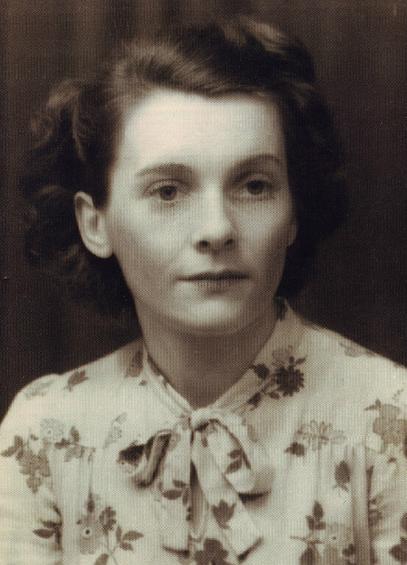 Black and white photo of a young Berthe Mayer. She has dark hair and is wearing a top with flowers, tied in a bow at the neck.