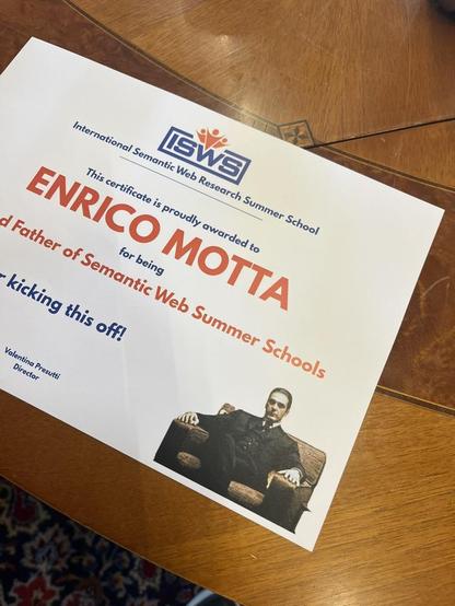 CErtificate for Enrico Mota, certifying him as "Godfather of Semantic Web Summer Schools". It shows a photo of Al Pacino as Michael Corleone from the movie The Godfather, but with the face of Enrico Motta