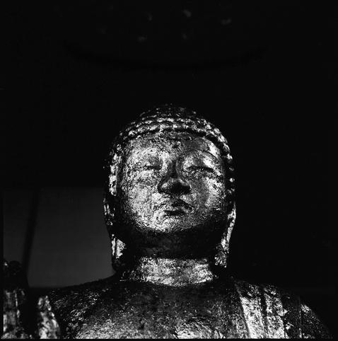 black and white photograph of a gilded, golden, buddha.