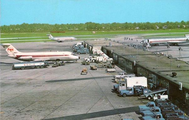 Airplane parked at a long terminal with sets of gates on each side.