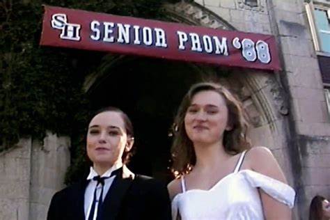 Dos mujeres posando frente a un cartel de "SENIOR PROM '88" en un entorno que sugiere un baile de graduación en una escuela secundaria.