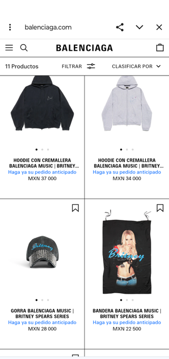 Pantalla de productos de la colaboración Balenciaga con Britney Spears, mostrando un hoodie negro y gris, una gorra y una bandera.