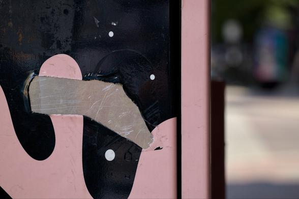A hole in a wrap on a utility box, exposing the metal underneath.